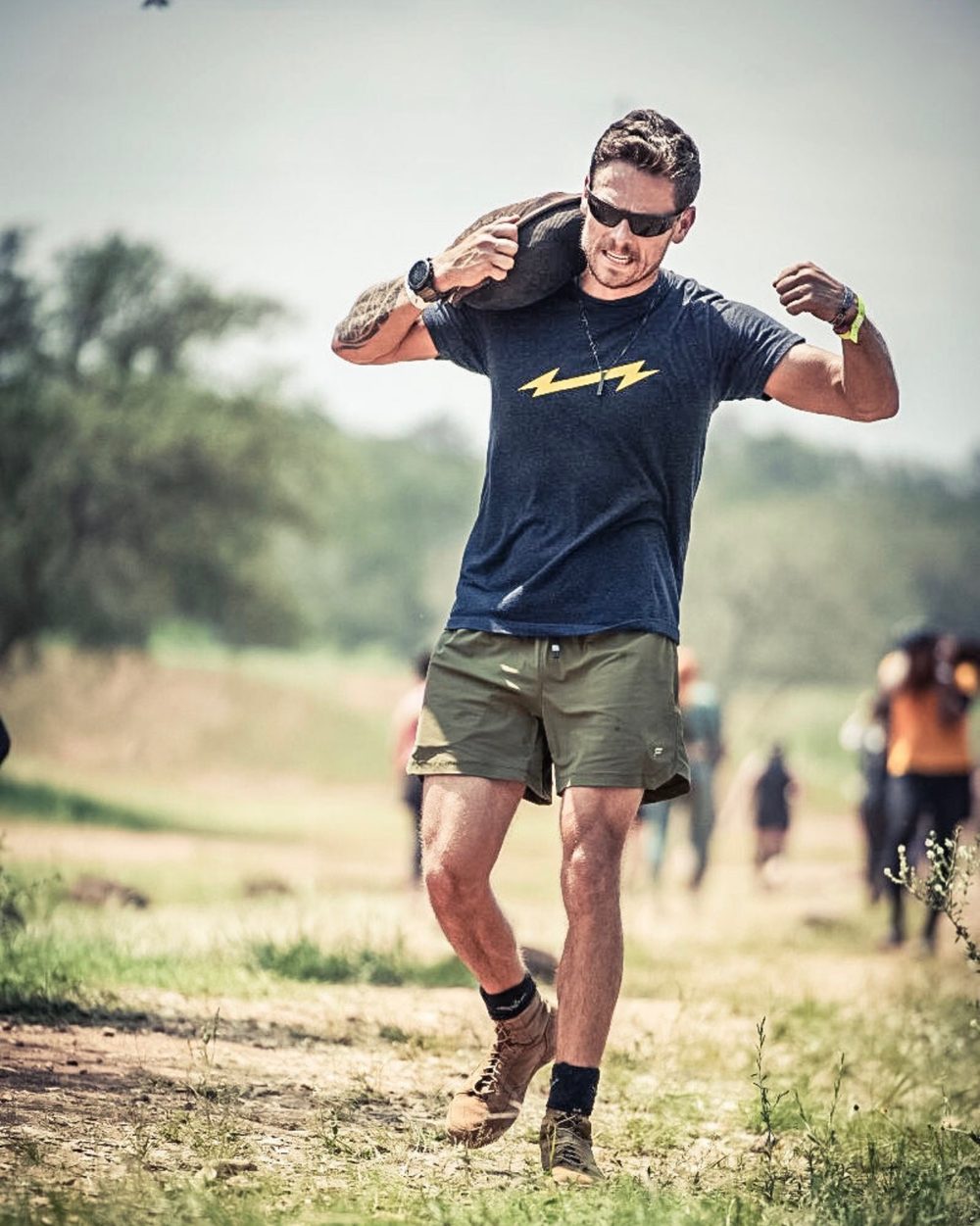 Jordan Smith, founder of First There Fitness, carrying a sandbag during a ruck